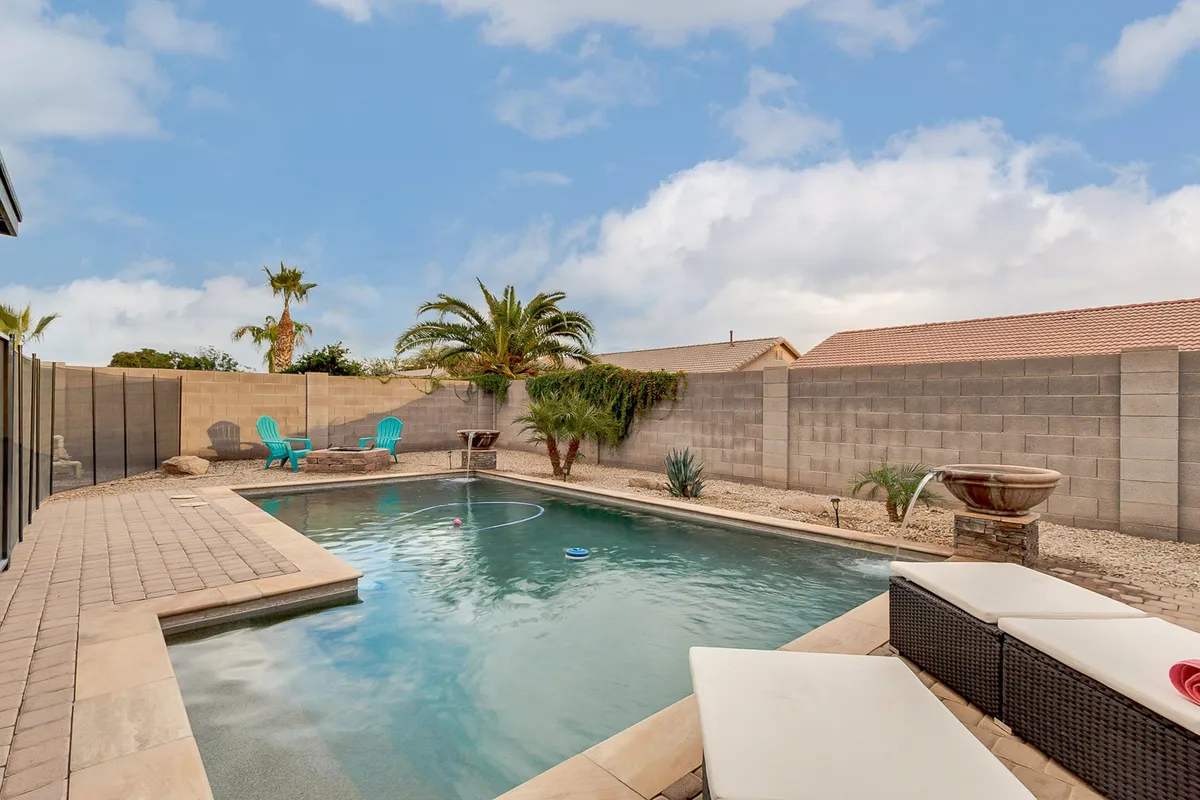 This exterior image showcases a sparkling swimming pool surrounded by lounge chairs and lush palm trees, with a welcoming patio area nearby. The tranquil setting exudes relaxation and offers a glimpse into the kind of family-friendly outdoor fun described in the section.