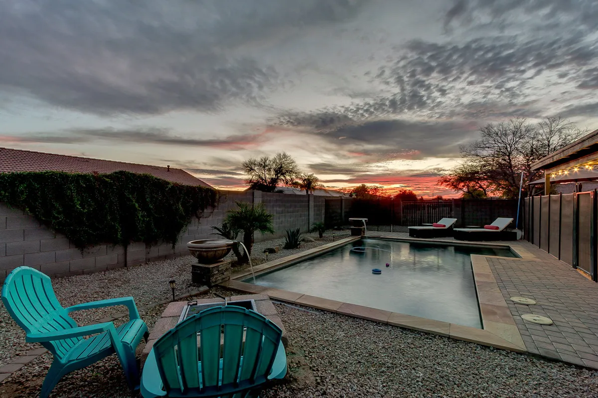 An inviting pool area bathed in the warm glow of sunset, complete with lounge chairs and a decorative pot, suggesting both active play and serene evening gatherings. The atmosphere is calm and welcoming, ideal for ending a day of exploration.