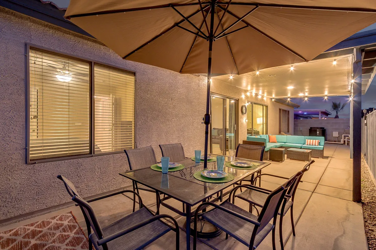 An inviting outdoor dining area with a table, comfortable seating, decorative string lights, and an umbrella. This space is ideal for outdoor meals, social gatherings, or simply relaxing in the evening, tying into the everyday convenience and lifestyle described in the section.