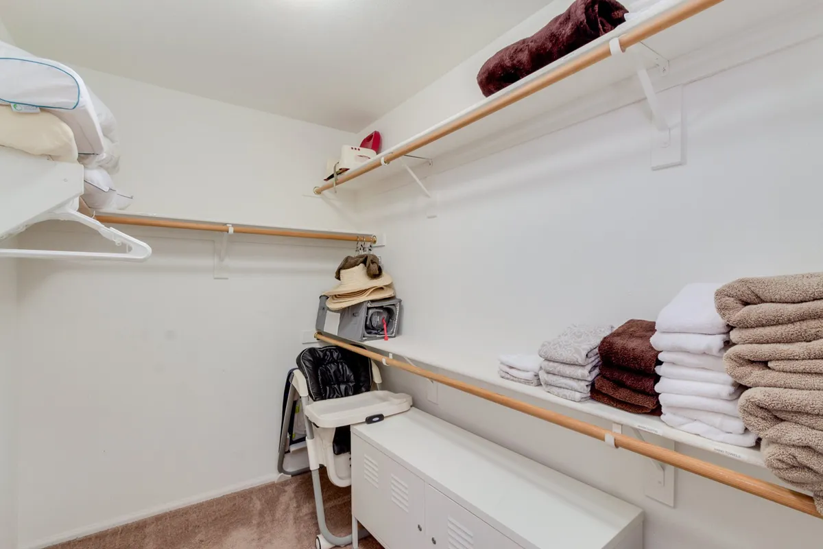 The scene shows organized shelves filled with neatly stacked towels, a folding chair, and a storage unit in an interior space, suggesting a well-equipped area for household chores and storage.